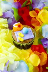 view of a cupcake with decorative miniature toppings surrounded by flowers.