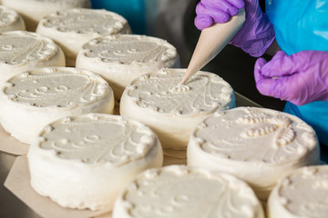 Ornament on white cakes. Hand with tool decorates cake. Just a bit of cream. So fresh and savoury.