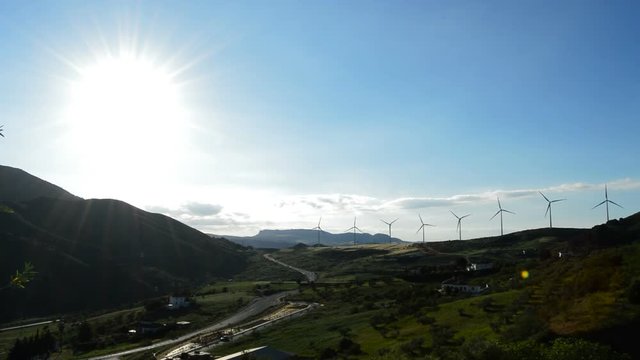 Landscape of wind turbines energy in the mountain with road at sun at sunset