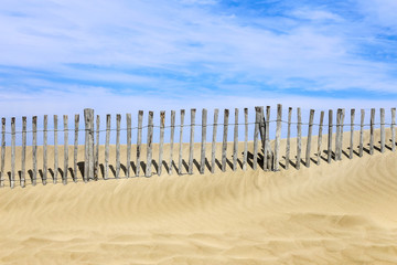 une barrière de bois à demie entérrée sur la crête d'une dune de plage