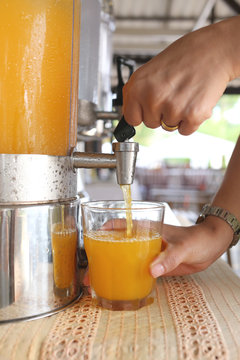 woman's hands were pressing orange juice into drink glass.