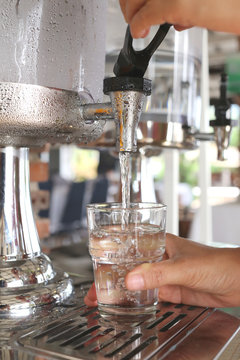 woman's hands were pressing cool water into drink glass.