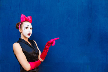 Mime points a finger at the center against a background of a blu