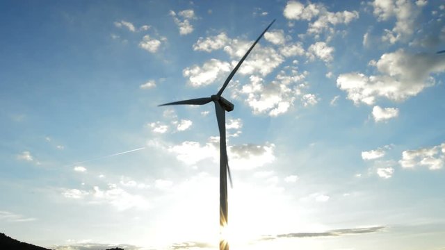 Wind turbine moving at sunset in a cloudy afternoon