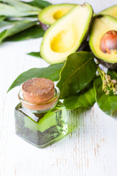 Avocado with leaves and jar of green avocado oil