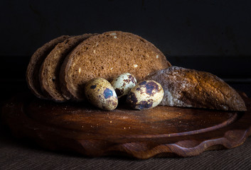 Fresh bread on wooden table,vintage filter, Traditional black rye-bread on dark background,   sliced bread and quail eggs, vintage still life