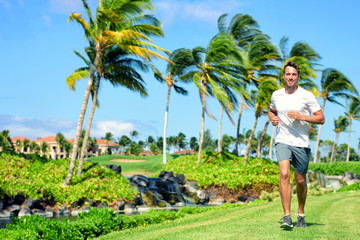 Coureur d& 39 homme au mode de vie actif faisant du jogging dans un quartier tropical américain résidentiel de luxe haut de gamme - vie à Miami en Floride. Athlète masculin de remise en forme en bonne santé qui fait du cardio sur l& 39 herbe en été.