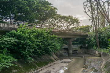 View of city bridge, water drainage and forest in Singapore city, color filtered