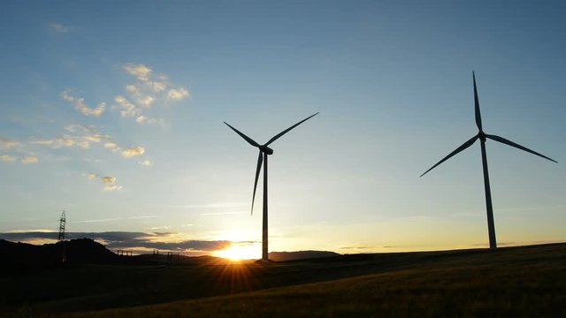 Wind turbine moving at field at sunset