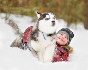 young boy playing with the dog in the snow
