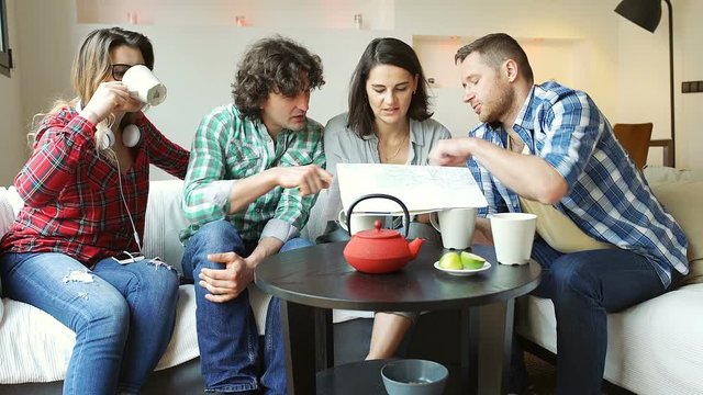 Friends looking on the map in their apartment and man drinking tea
