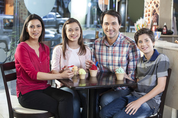Smiling Family With Ice Creams At Table In Parlor