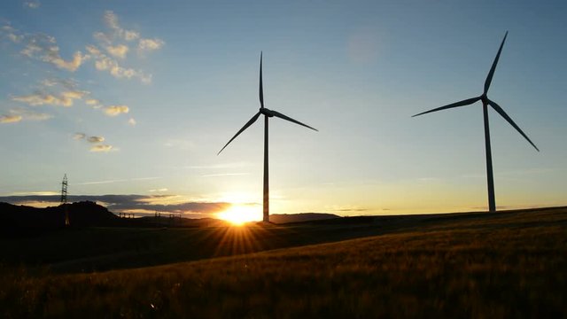 Wind turbine rotating at sunset in a field