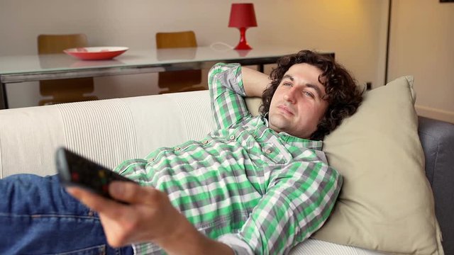 Man lying on the sofa and watching television in the living room
