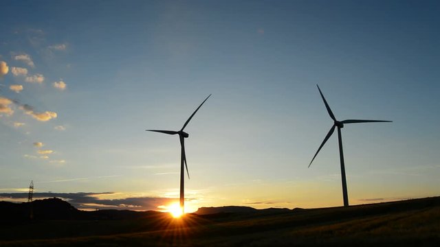 Wind turbine rotating in field at sunset at cloudy day