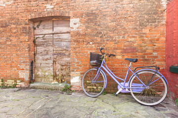 Fototapeta na wymiar old violet bicycle parked long an external wall in Burano island
