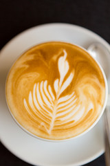 Coffee on dark background with shape of flower in the cream