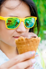 Portrait of Beautiful Young Woman  in yellow sunglasses with an Ice Cream Cone, closeup.