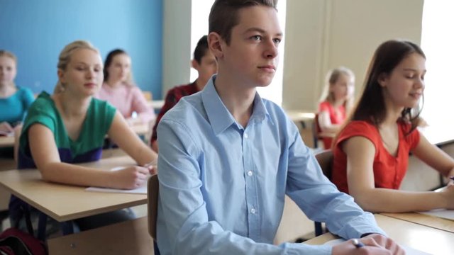 students with notebooks writing test at school