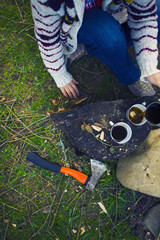 The girl prepares coffee in nature.