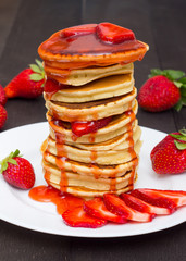 Fresh pancake stack with syrup streaks decorated with strawberries