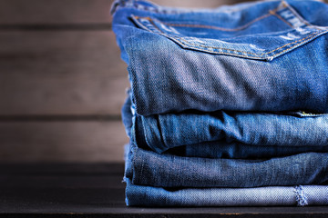 Few pair of jeans stacked on a wooden background