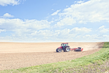 Tractor compresses the soil after planting with rollers.