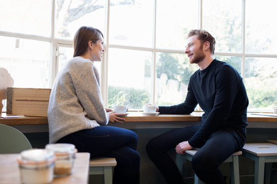  Young Couple Sitting At Table In Coffee Shop Together	
