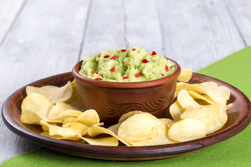 bowl of guacamole dip and potato chips