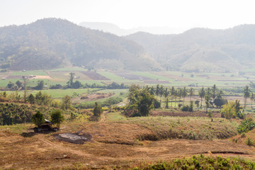 Countryside farm field surrounded by mountain with haze
