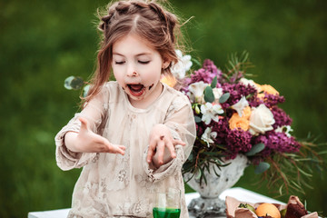 Little baby girl eats chocolate cake in nature at a picnic. The concept of a happy childhood