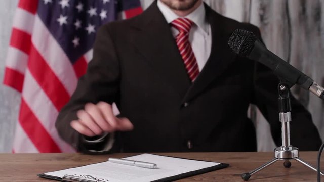 USA flag, businessman and microphone. Guy gesturing and speaking. Always stay confident. Information from city official.