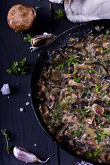 Roasted  champignons mushrooms with meat, butter, parsley and roasted garlic in black bowl. Selective focus. Healthy food concept.