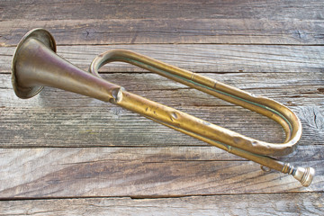Fototapeta na wymiar Old broken army trumpet on wooden background