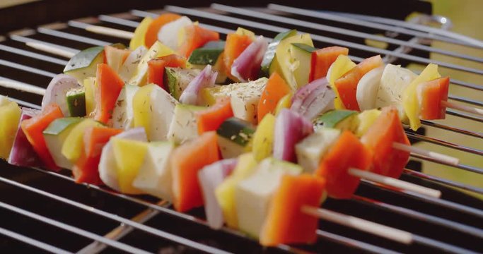 Healthy colorful kebabs with assorted fresh diced vegetables grilling over an outdoors portable barbecue in summer  close up view