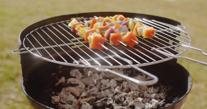 Colorful vegetable kebabs grilling on a BBQ outdoors on a lawn in summer in a healthy diet concept