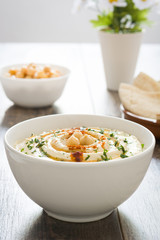 Hummus with pita bread on rustic wood