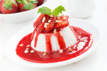 Vanilla panna cotta with strawberry sauce on a plate, horizontal