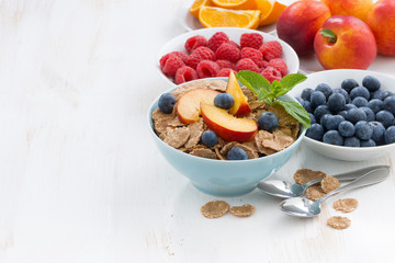 whole-grain flakes with fruit and berries on white wooden table