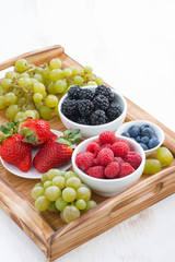 wooden tray with fresh berries and grapes, vertical, top view