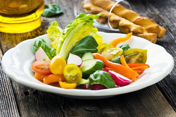 Delicious fresh organic salad with homemade pesto on the plate and on the wooden background