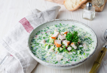 Okroshka with smoked chicken breast - Russian cold soup with vegetables on white wooden background. Selective focus