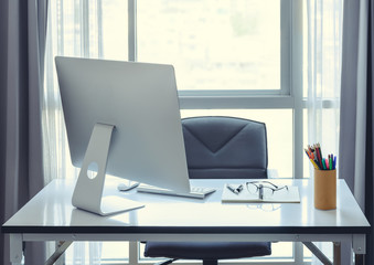 Office desk with desktop computer, cup of coffee and office equi