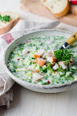 Okroshka with smoked chicken breast - Russian cold soup with vegetables on white wooden background. Selective focus