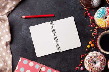 Notepad, donuts and coffee on stone table