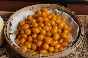 A lot fresh yellow tomatoes in basket.