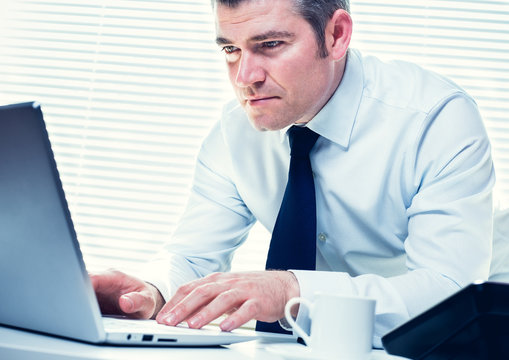 Insurance Investigator On His Laptop, Following A Lead On A Fraudulent Claim. Business, Insurance, Corporate And Career Concept