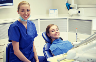 Obraz premium happy female dentist with patient girl at clinic