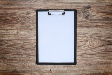 Blank white paper sheet A4 on clipboard. Wooden background.