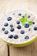 Buckwheat porridge in a bowl with mint leaves and blueberries.